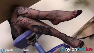 Sotto al tavolo, I piedi in collant della segretaria tatuata