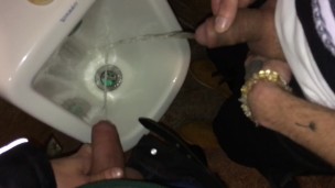 Boys piss and spit together at the urinal after some cocktails