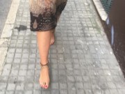 young female hippie is walking barefoot in public street