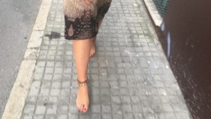 young female hippie is walking barefoot in public street