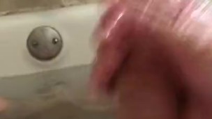 Stroking cock and hairy balls in bathtub with baby oil.