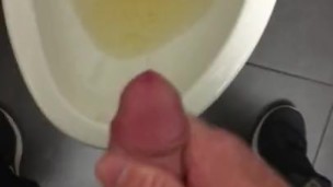 POV pissing into a toilet in a public bathroom and jerking off and cumming