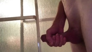 Guy strokes his cock, standing in the shower until he cums