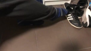 Male shoeplay in striped socks and different sneakers and watching a movie