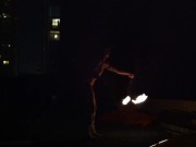Blond guy spins fire on rooftop in socks and underwear