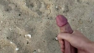 Horny twink jerks his big uncut cock on the beach 