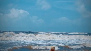 Tik Tok. Beach Voyeur looks on Blonde Teen enjoying Topless in the waves. 
