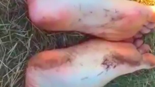 Solo guy rubbing feet in dirt outdoors
