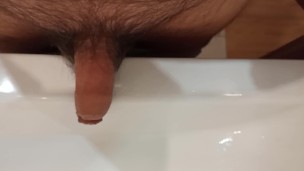 The boy is pissing into the washstand.