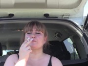 A cute bbw smokes in the street near the car