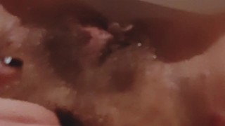 大きな猫の唇で毛むくじゃらのブッシュを指で触れている熱い熟女