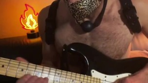 Guy with a ball gag plays guitar 