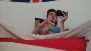 Twink jerks off his big cock and ejaculates while watching a porno