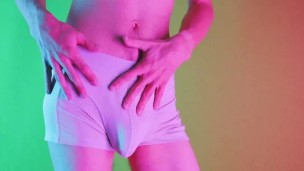 Sensual moves on colored background, showing bulge and hairy soft cock