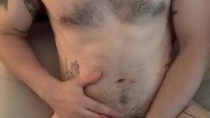 Cute guy in bed cumming on his chest and stomach