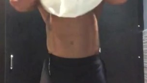 Fit tattooed man strips in gym locker room