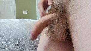 Hairy guy playing with his big cock on the edge of bed