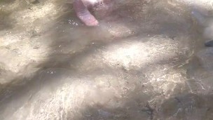 Cute long hair girl on her knees looking for shells to collect in popular spring creek