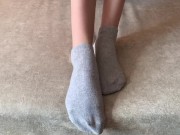 The girl her legs and takes off her socks with her feet 1/16