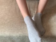 The girl her legs and takes off her socks with her feet 5/16