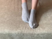 The girl her legs and takes off her socks with her feet