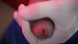 A man masturbates his penis on a chair wearing red and white gloves