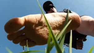 Jon Arteen walks barefoot on the grass, shows the soles of his feet in close-up, does the giant feet