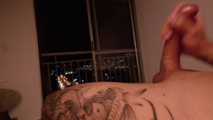 Colombiano se hace una rica paja en su cama con vista a la ciudad hasta venirse.