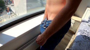 boy jerks his big dick by the window