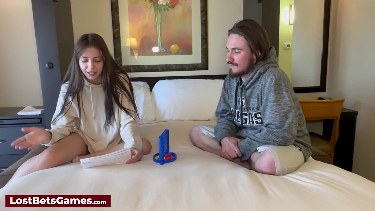 A couple playing a strip game on the bed when she loses to ...