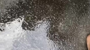 pov squirting a puddle in the street while cars drive by