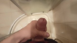 The guy masturbates his dick standing in the shower and cums