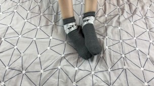 Girl with long legs caresses her feet in gray New Year socks with deer