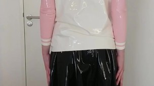 Putting on latex schoolgirl uniform shirt over rubber skirt, blouse, latex layers