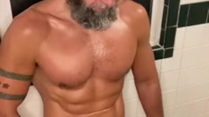 Muscular bearded man pisses in showet